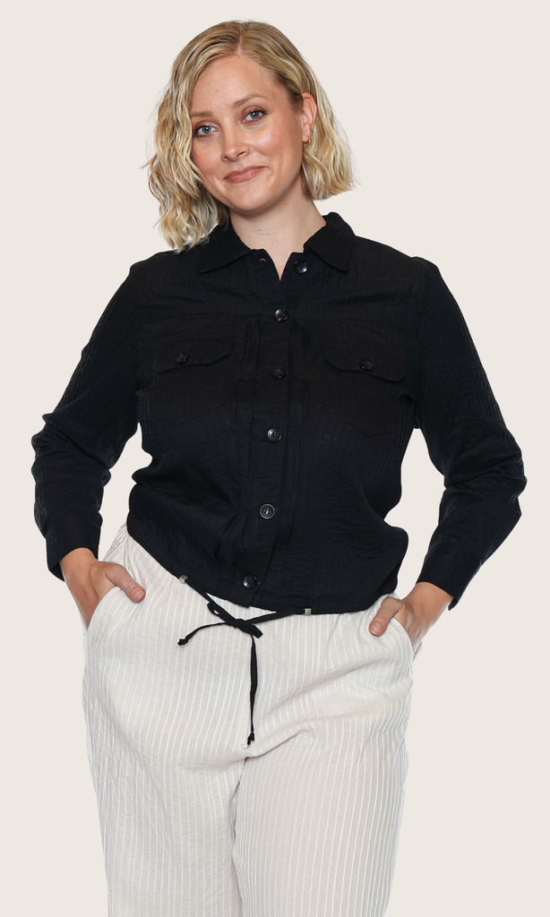 Woman wearing a black shirt and white pants on a plain background
