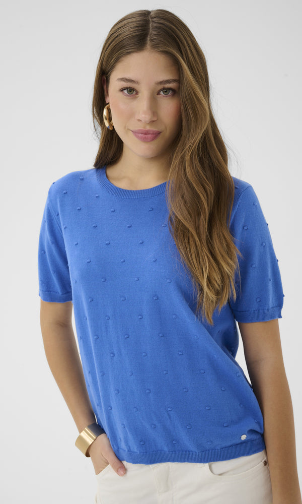 Woman wearing a blue t-shirt with small patterns against a white background