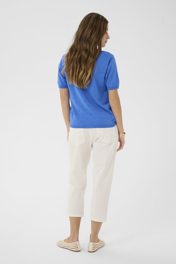 Woman wearing a blue shirt and white pants on a white background
