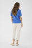 Woman wearing a blue shirt and white pants on a white background