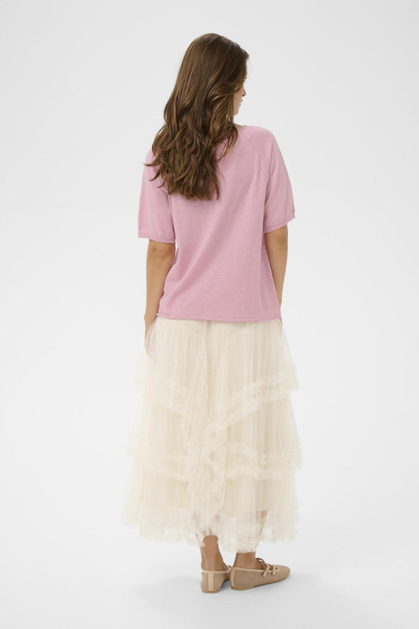 Woman wearing a pink top and white tulle skirt on a white background