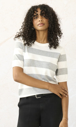 Woman wearing a striped sweater and black pants on a white background