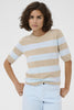 Woman wearing a beige and light blue striped sweater with light blue jeans on a white background