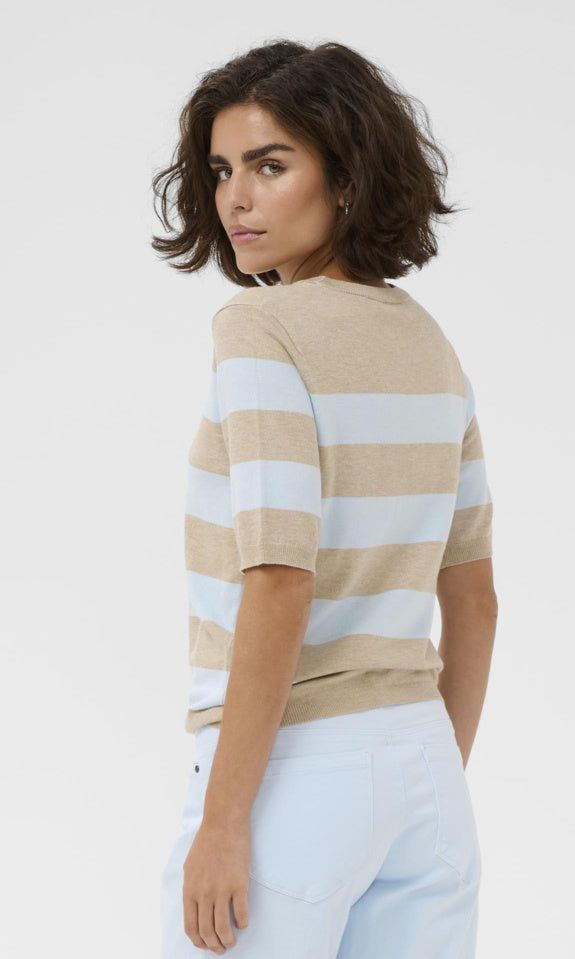 Woman wearing a beige and white striped shirt on a plain background