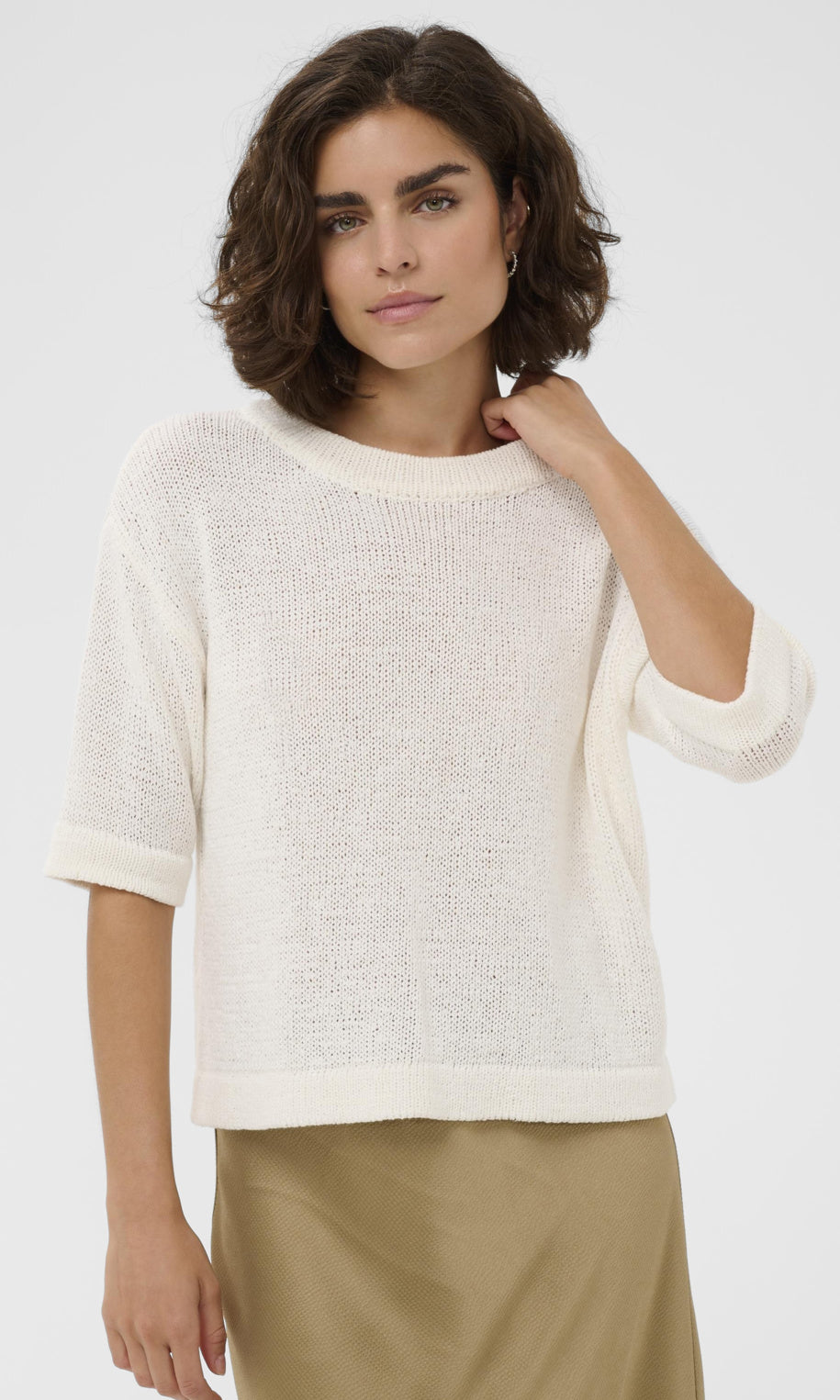 Woman wearing a white textured sweater against a plain background