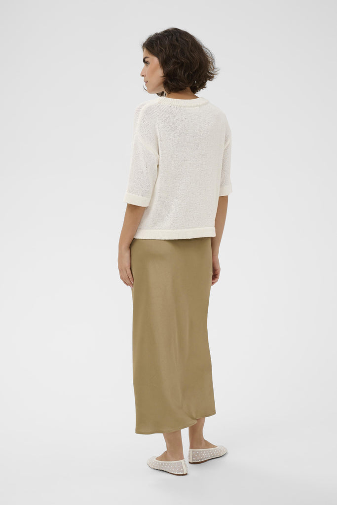 Woman wearing a white top and beige pants on a white background