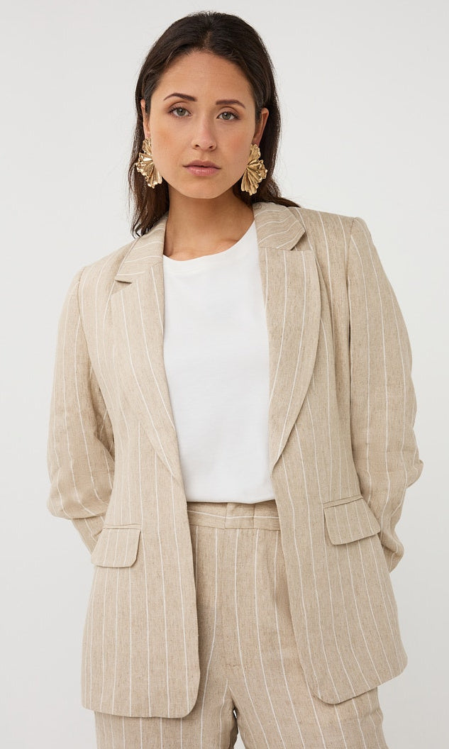Woman wearing a beige pinstripe suit with a white top on a white background