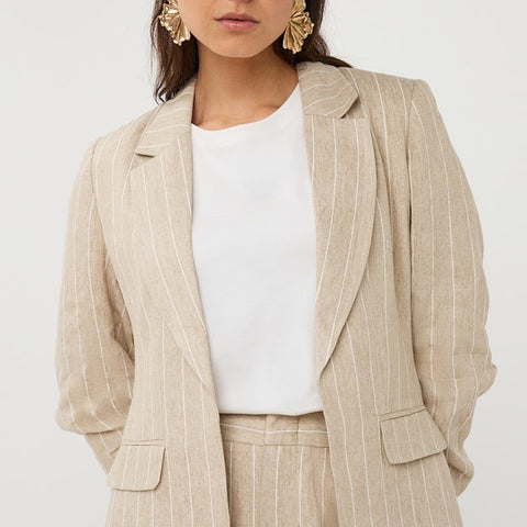 Woman wearing a beige pinstripe suit with a white top on a white background