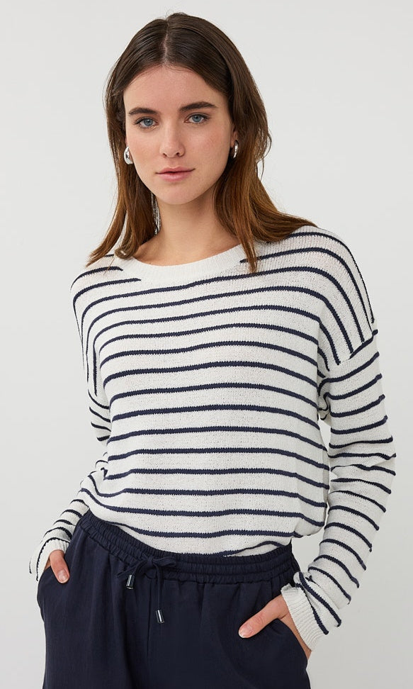 Woman wearing a black and white striped sweater with navy pants on a white background