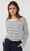 Woman wearing a black and white striped sweater with navy pants on a white background