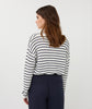 Woman wearing a black and white striped sweater and navy pants on a white background