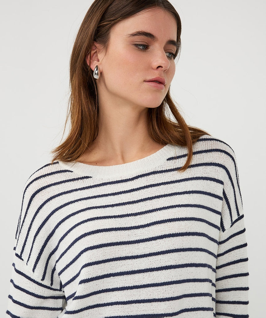Woman wearing a white and navy striped sweater on a plain background