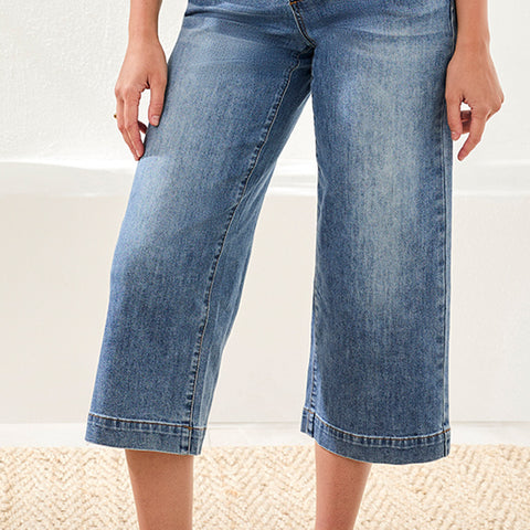 Woman wearing blue denim wide-leg jeans on a neutral background