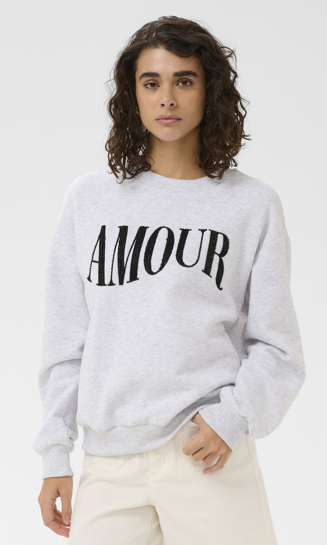 Person wearing a gray sweatshirt with 'AMOUR' printed on it against a white background