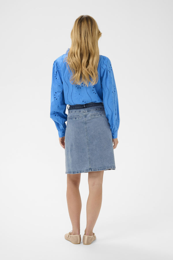 Person wearing a blue denim skirt and blue blouse on a white background