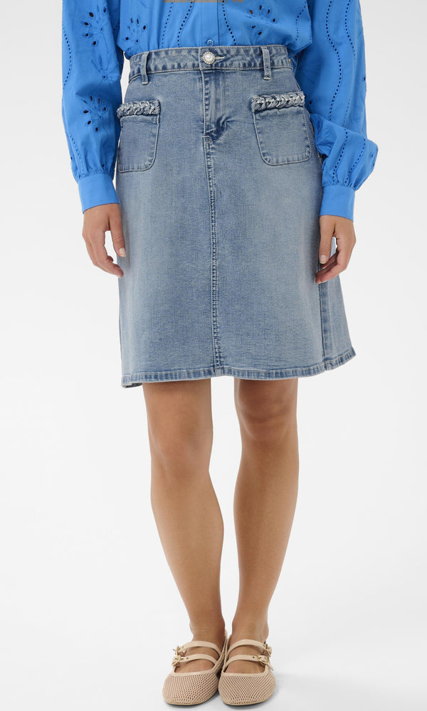 Person wearing a blue denim skirt and blue sweater on a white background