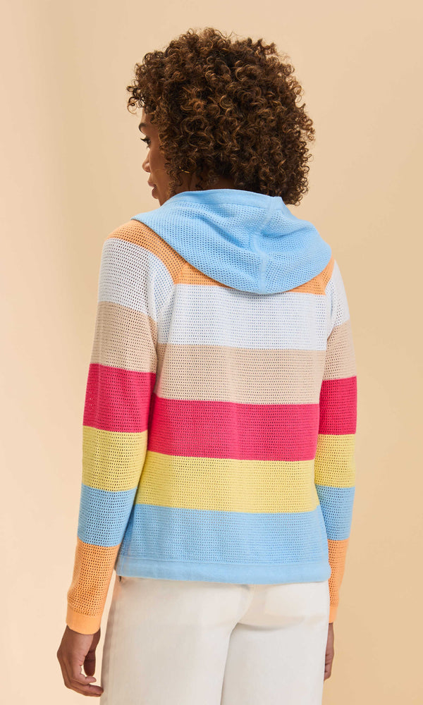 Person wearing a colorful striped sweater with a hood against a beige background