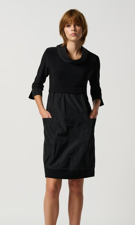A knee-length black dress with a mock neckline, long cuffed sleeves, and front pockets.