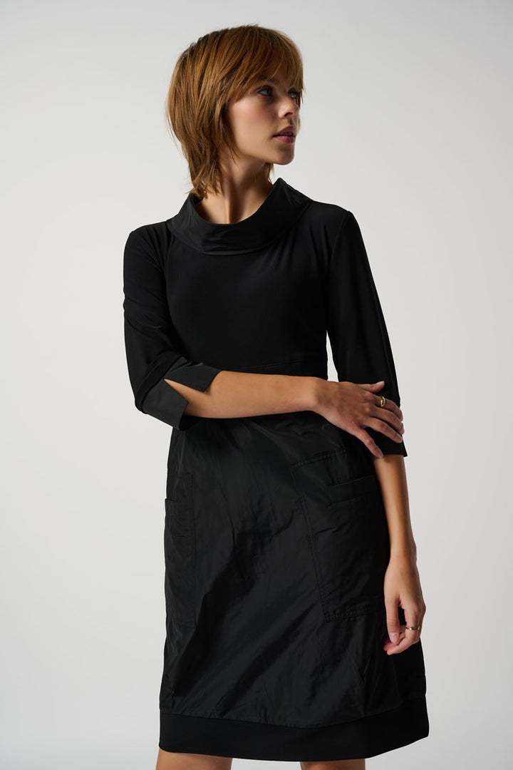 A knee-length black dress with a mock neckline, long cuffed sleeves, and front pockets.