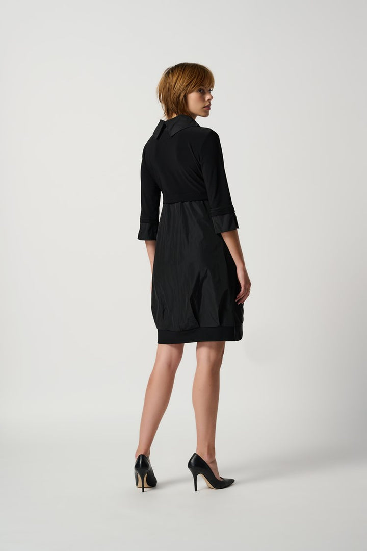 Back of a knee-length black dress with a mock neckline, long cuffed sleeves, and front pockets.