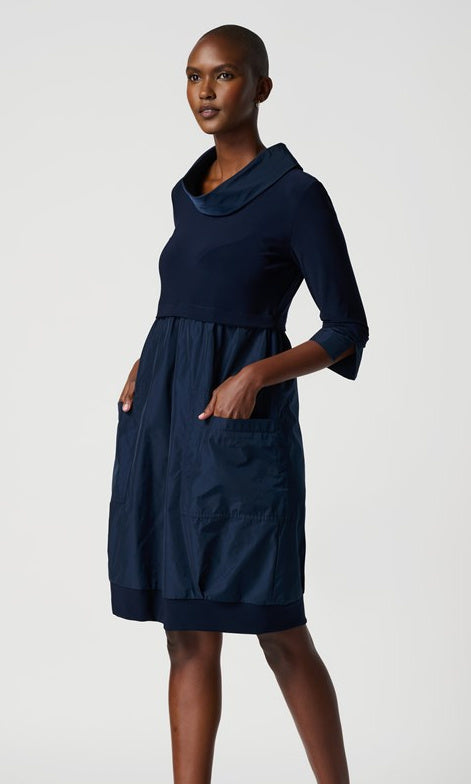A knee-length navy dress with a mock neckline, long cuffed sleeves, and front pockets.