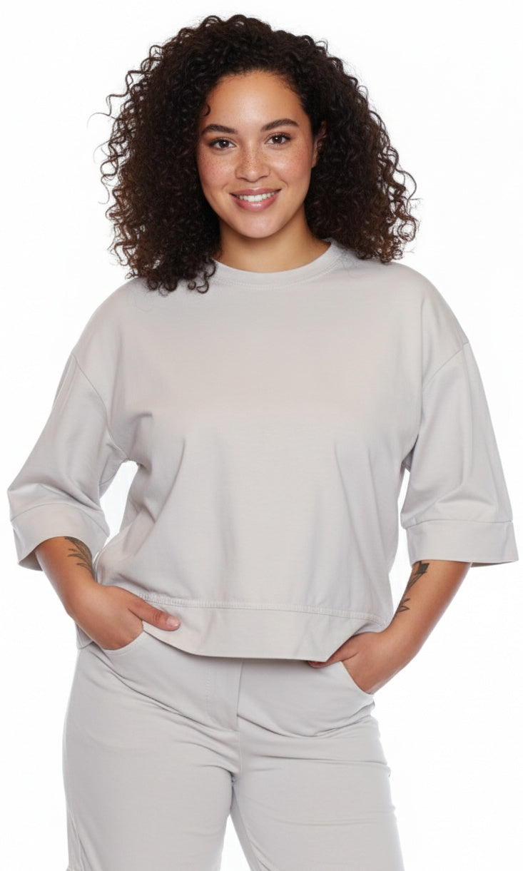 Woman wearing a light gray sweatshirt and pants on a white background