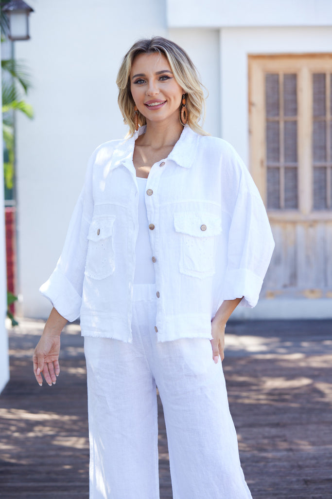 Woman wearing a white outfit standing outdoors with a building in the background