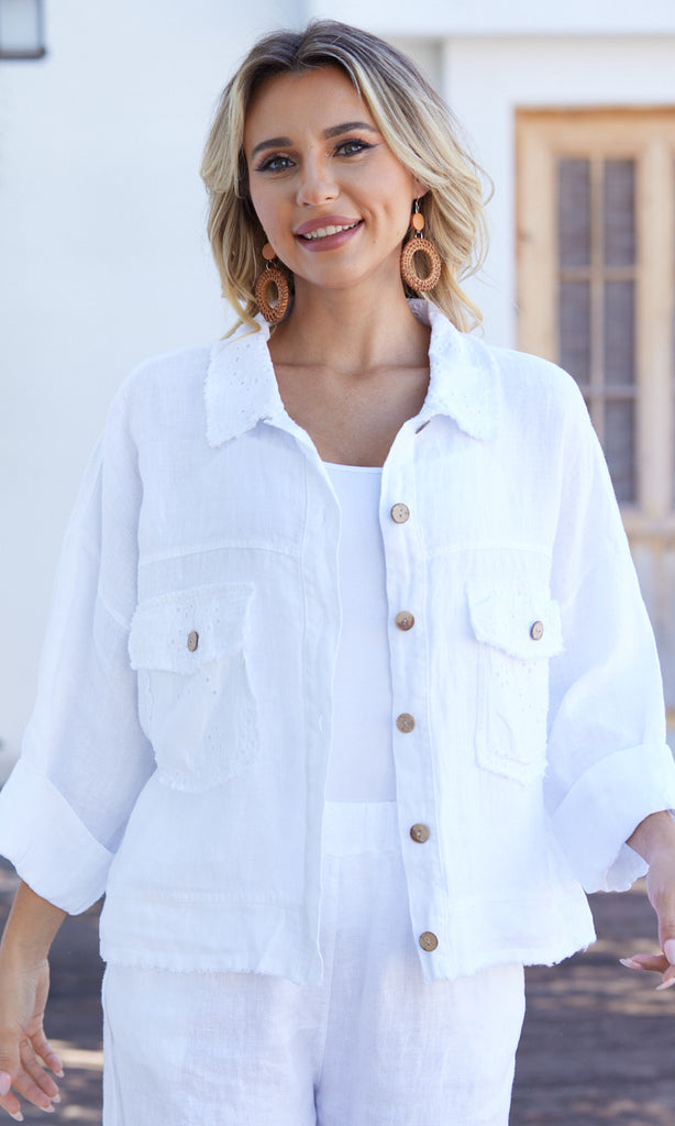 Woman wearing a white denim jacket with wooden buttons outdoors.