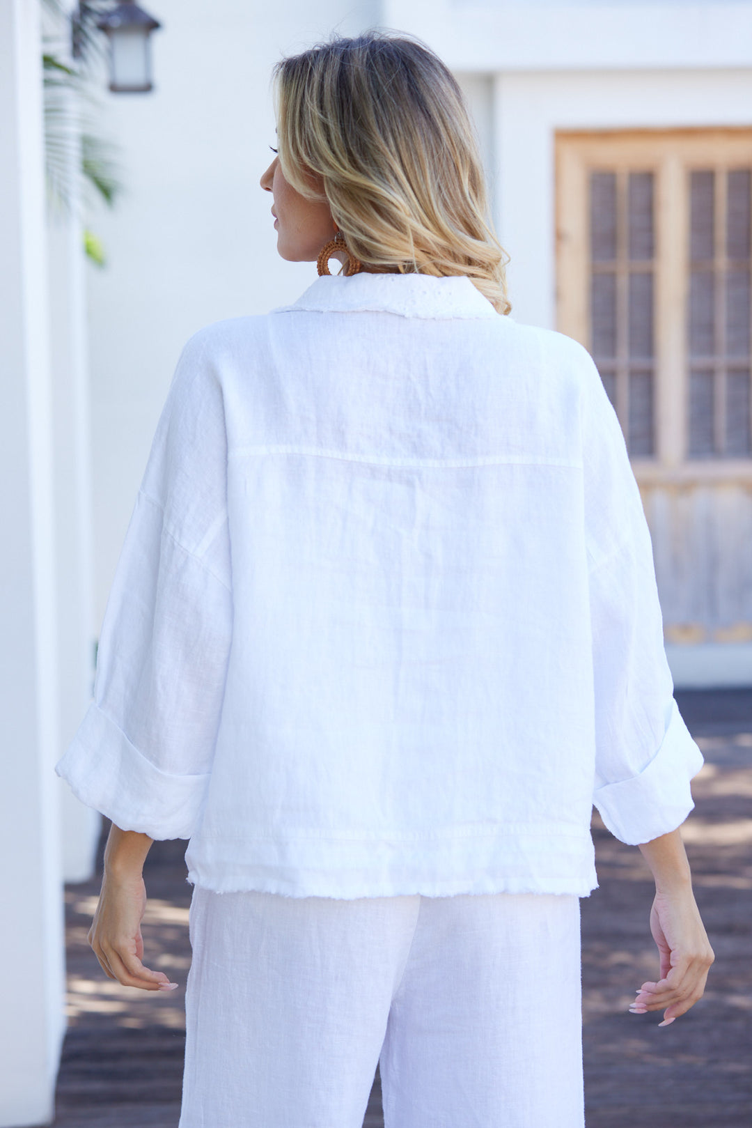 Person wearing a white linen shirt and pants outdoors.