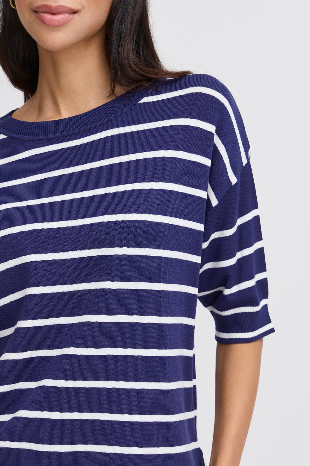 Navy and white striped shirt worn by a person on a light gray background