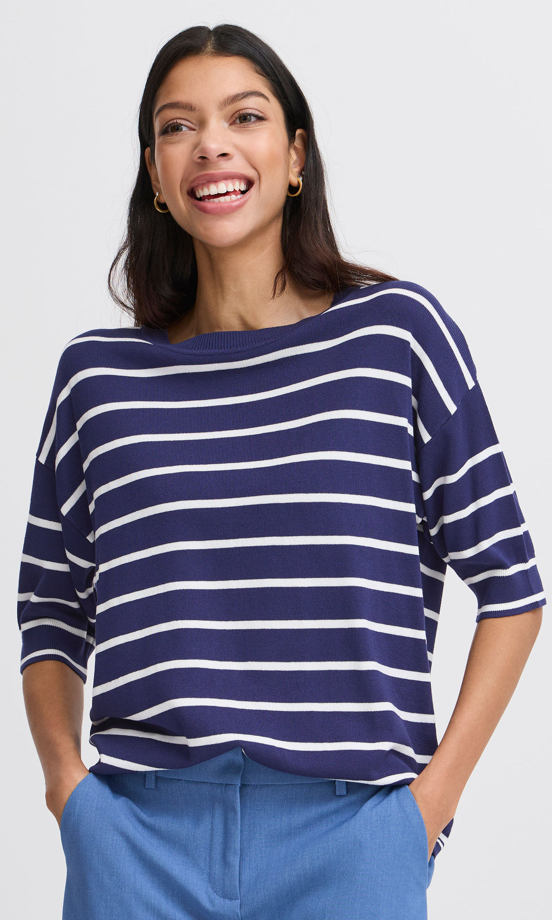 Woman wearing a blue and white striped sweater with a plain background