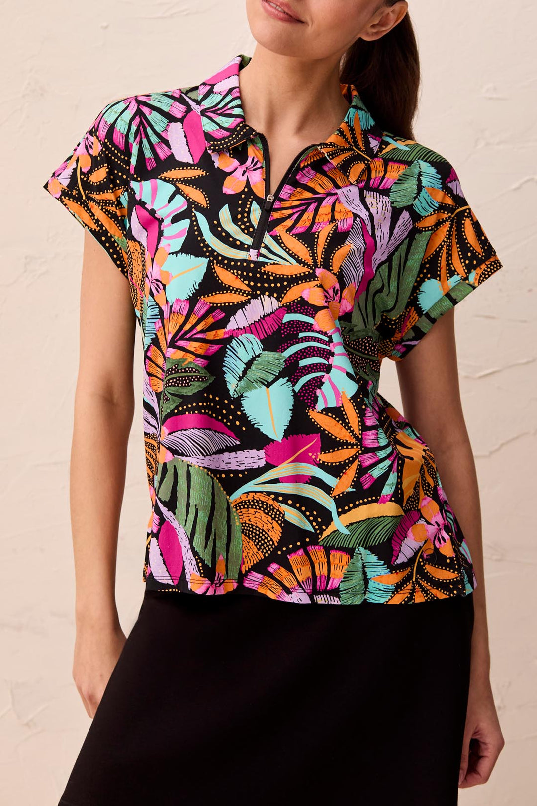 Woman wearing a colorful patterned blouse against a beige background