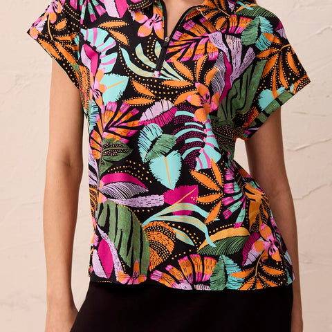 Woman wearing a colorful patterned blouse against a beige background