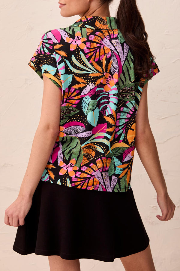 Woman wearing a colorful patterned top with a plain background