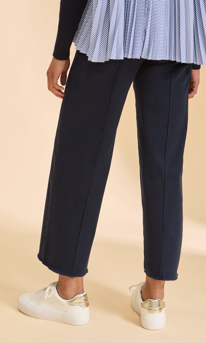 Navy pants worn by a person on a beige background