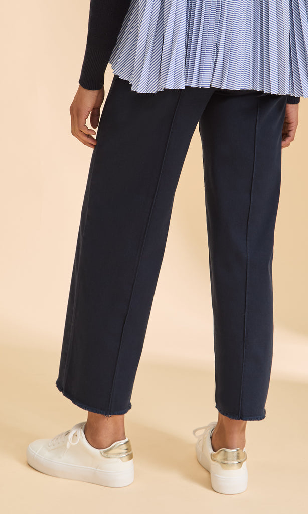 Navy pants worn by a person on a beige background