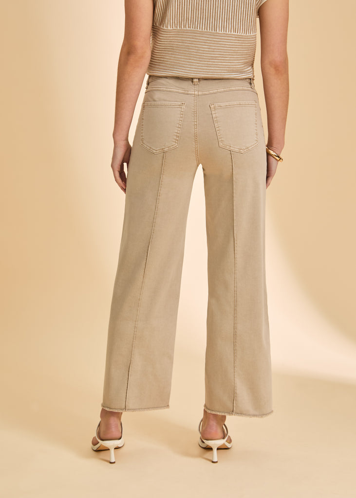 Person wearing beige wide-leg pants and a matching top on a beige background