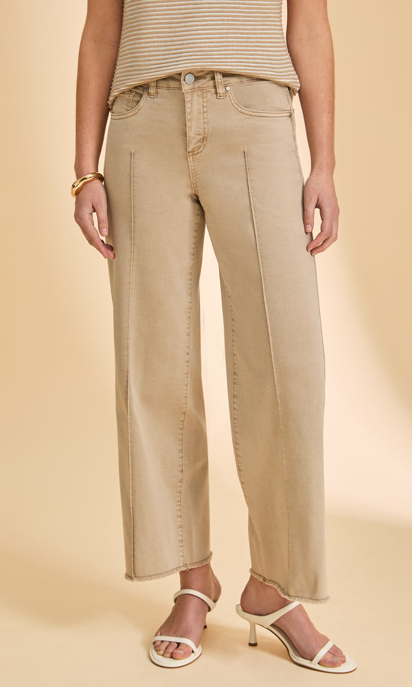 Person wearing beige jeans and a striped top on a beige background