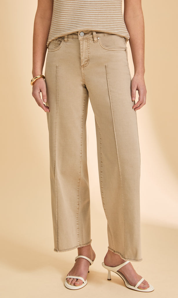 Person wearing beige jeans and a striped top on a beige background