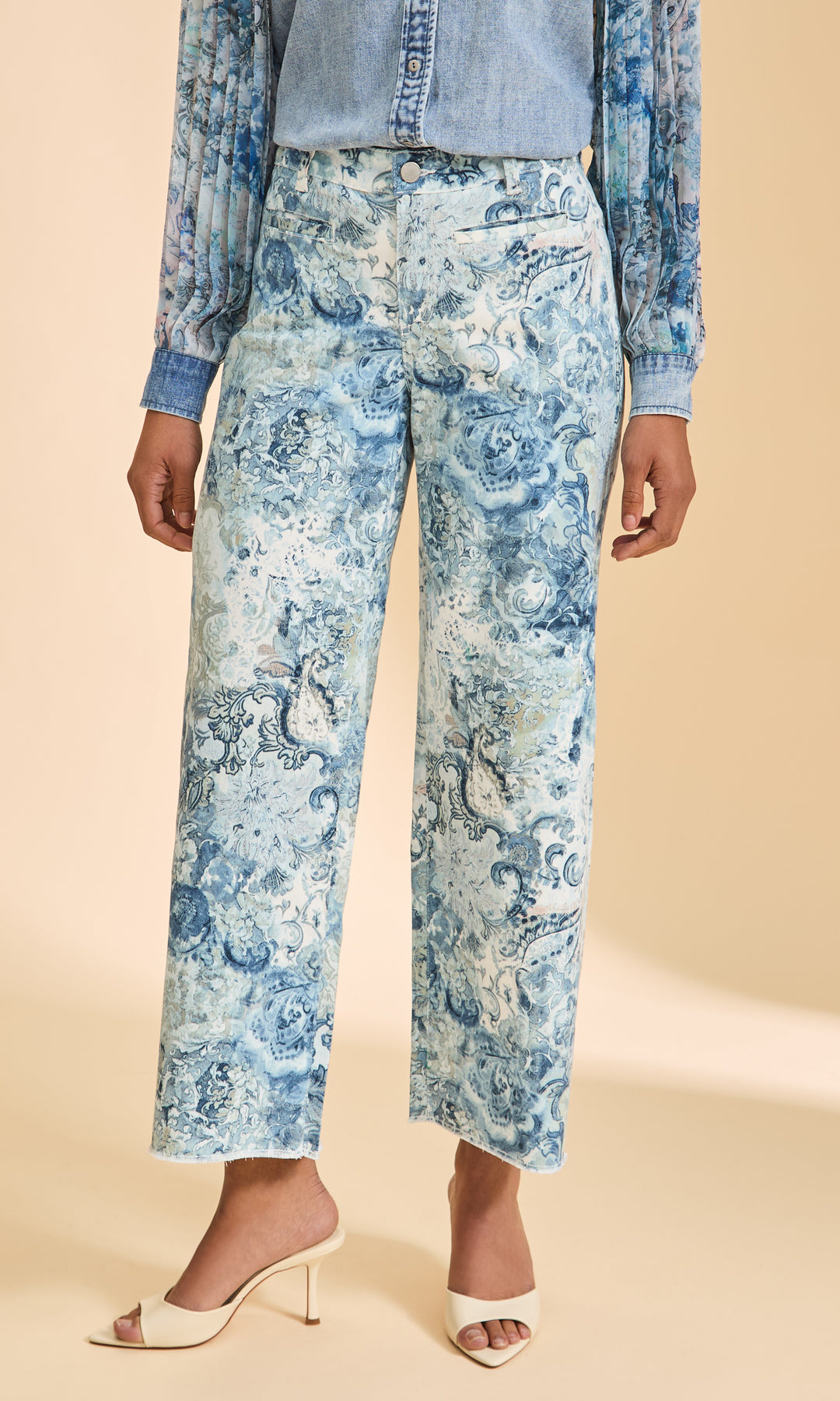 Woman wearing blue floral pants with a beige background