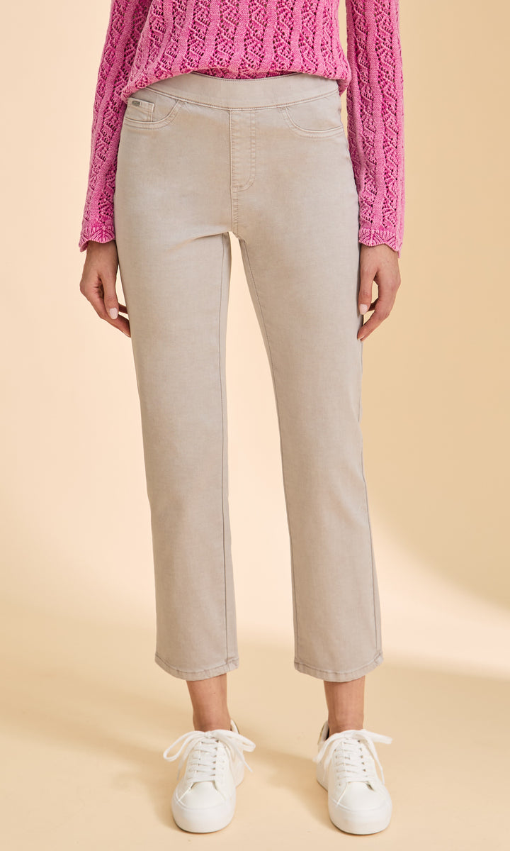 Person wearing beige pants with a pink sweater on a beige background