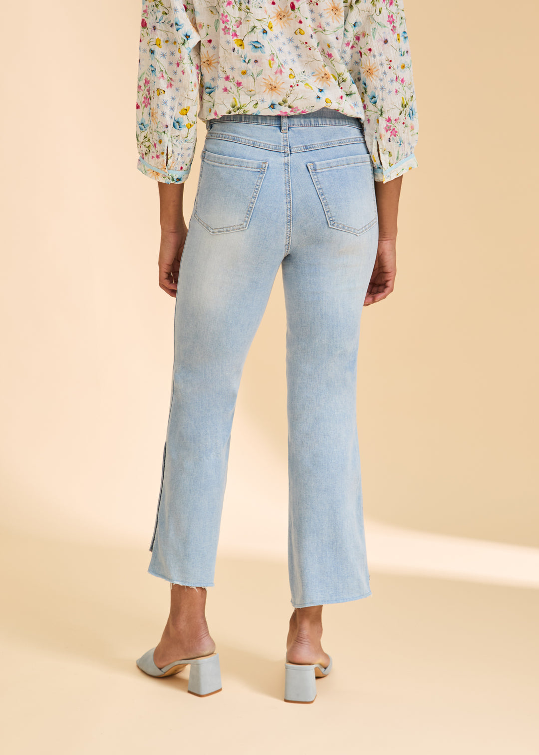 Light blue jeans worn by a person on a beige background