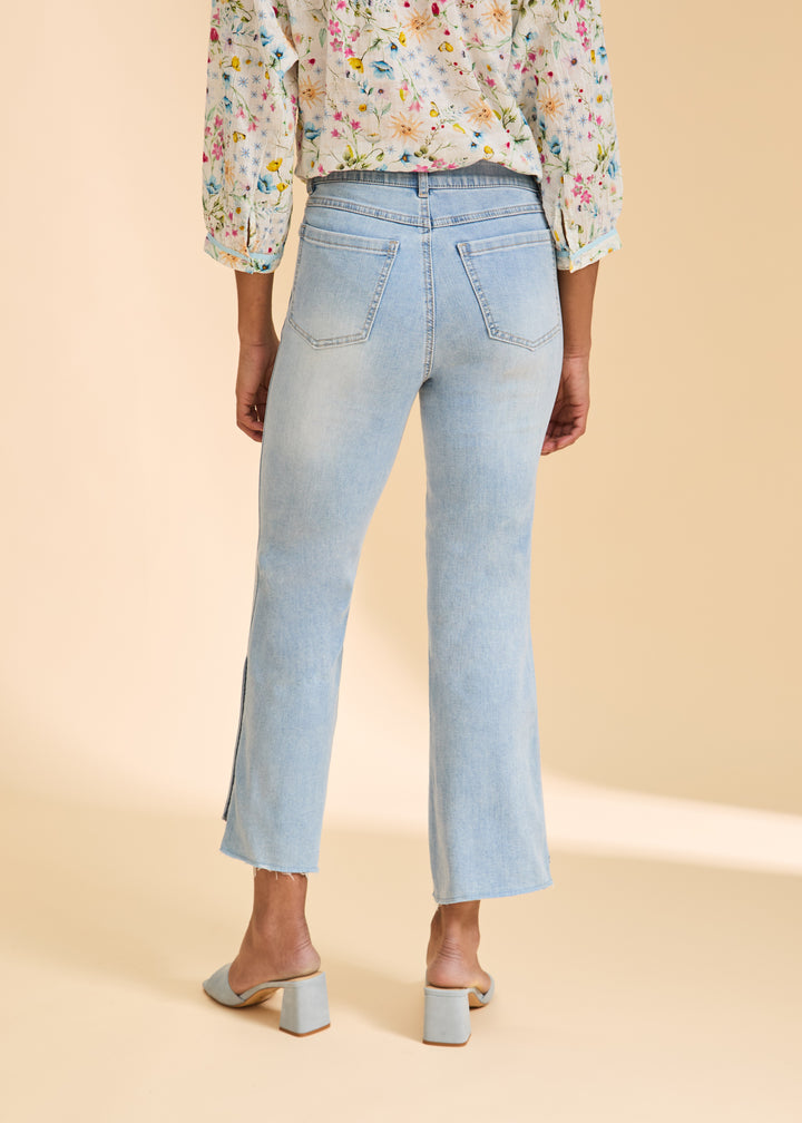 Light blue jeans worn by a person on a beige background