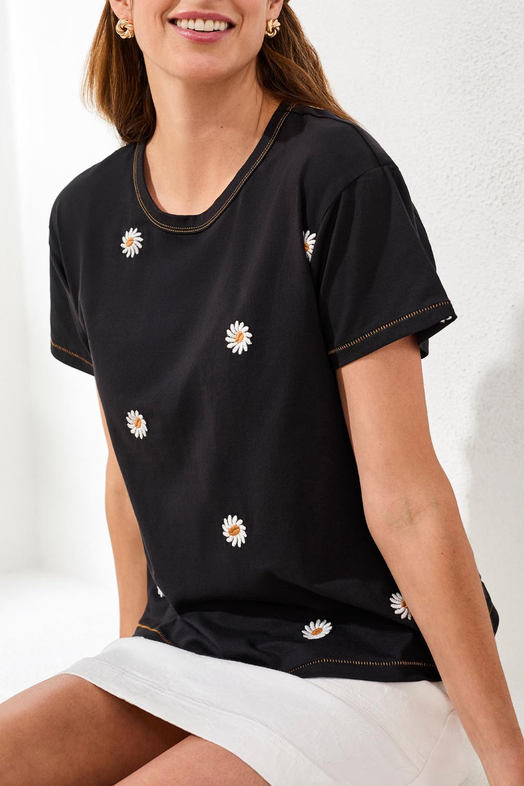Woman wearing a black t-shirt with white daisy patterns on a white background