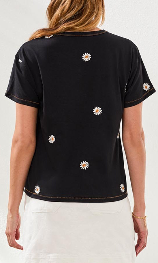 Black t-shirt with white floral patterns worn by a person on a light gray background