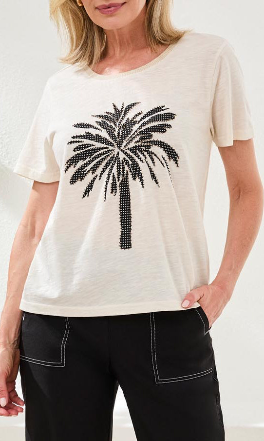 Woman wearing a white t-shirt with a black palm tree design on a plain background
