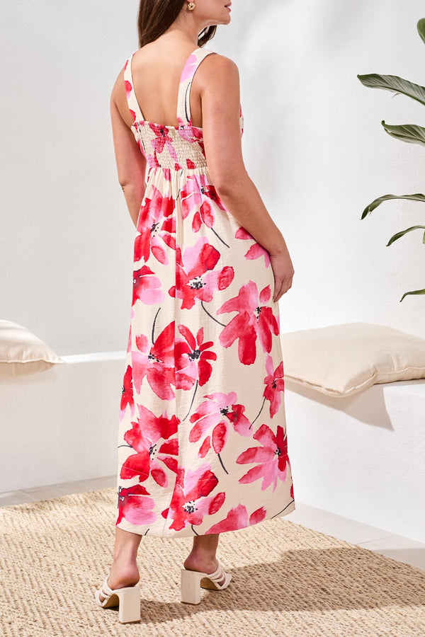 Woman wearing a floral dress with red and pink flowers in a minimal indoor setting.