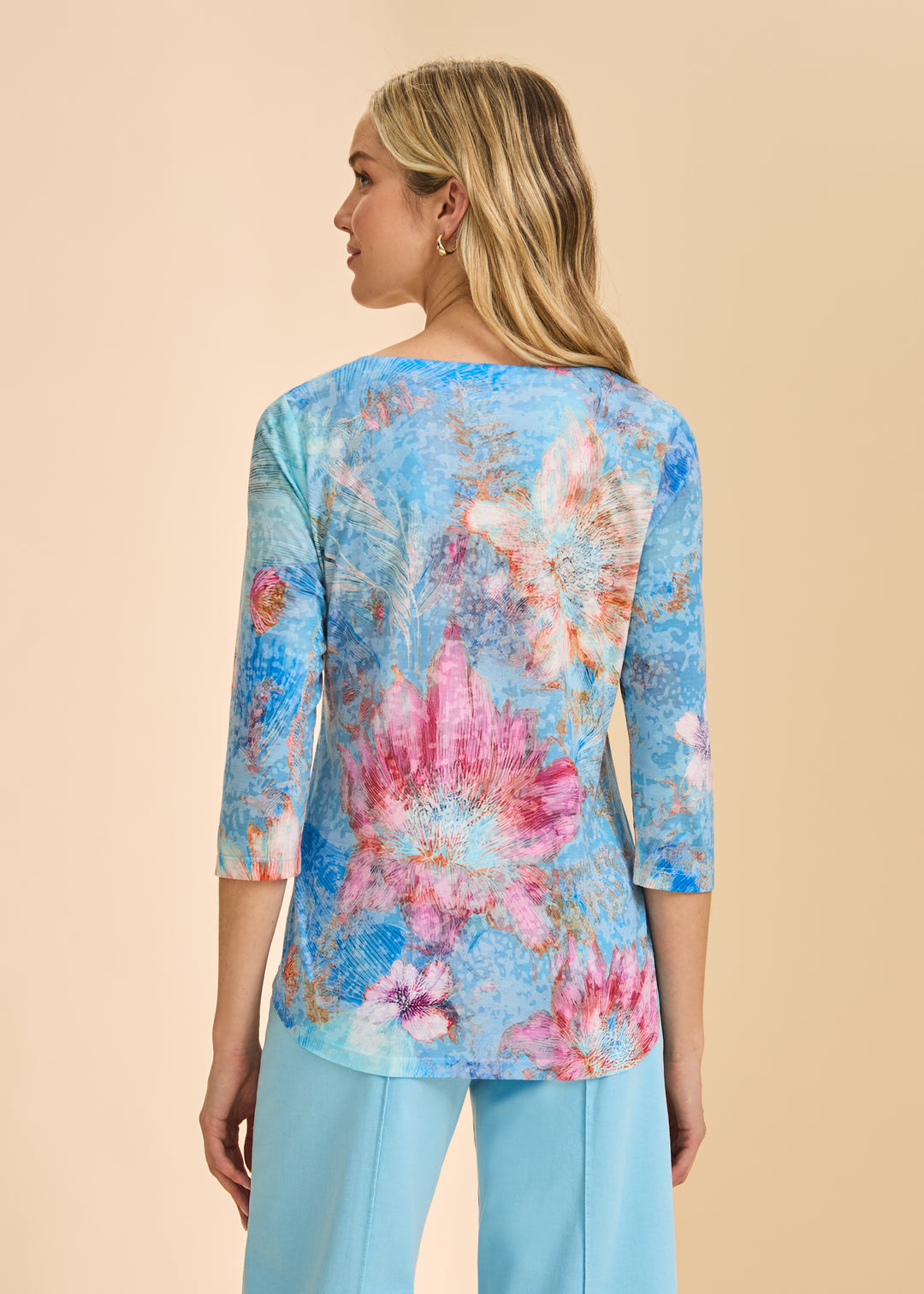Woman wearing a colorful floral blouse with a beige background