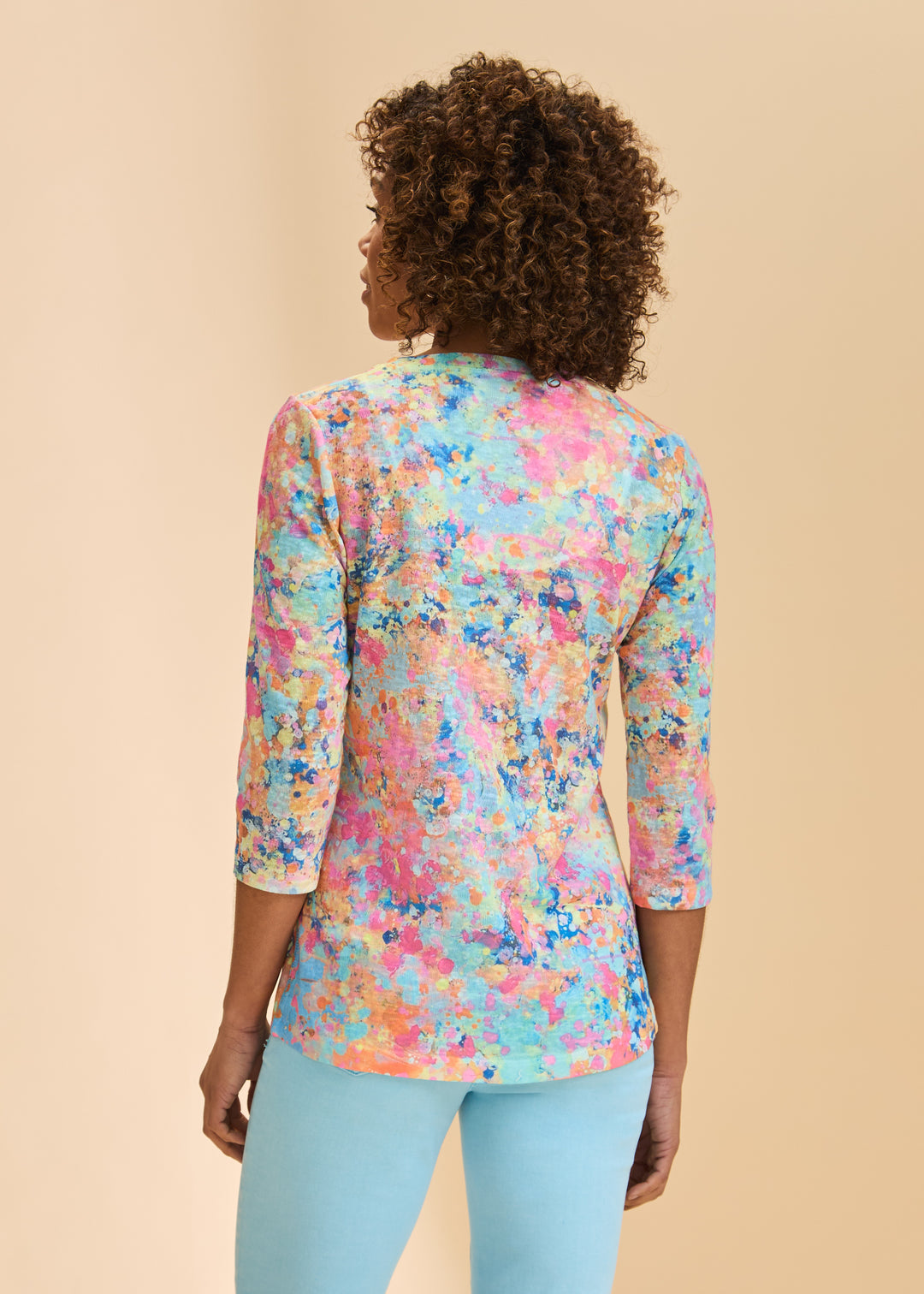 Person wearing a colorful floral blouse with a beige background