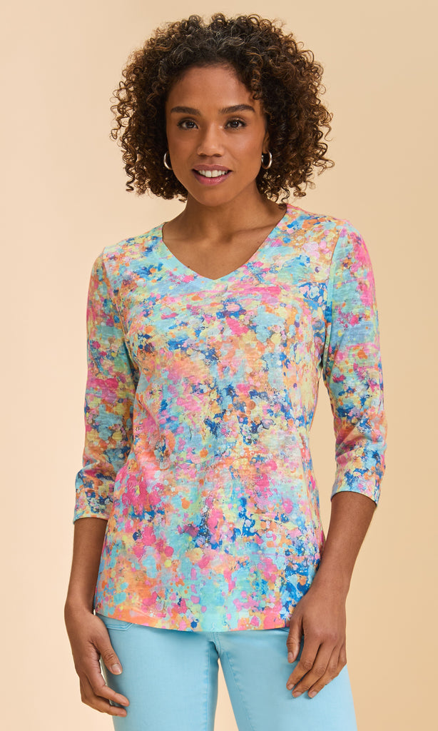 Woman wearing a colorful floral-patterned shirt against a beige background